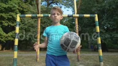 自信的男孩足球运动员带着球看镜头，欢迎参加比赛